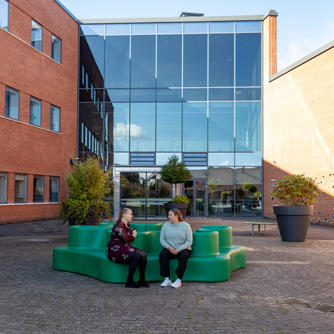 En gruppe studerende sidder på bænke i studiemiljøet på campus Viborg. Hygge, afslapning og socialt samvær.